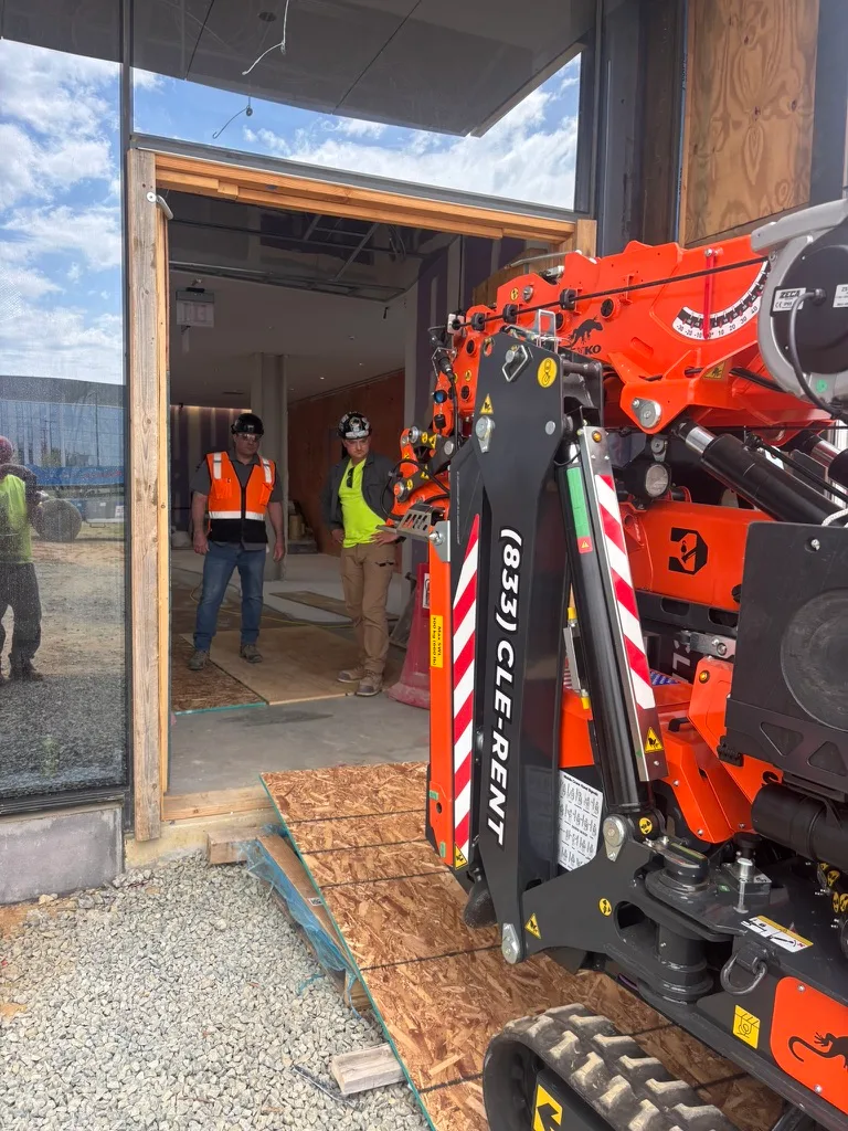 Jekko SPX532.2 mini crane lined up to track through a framed doorway on a jobsite