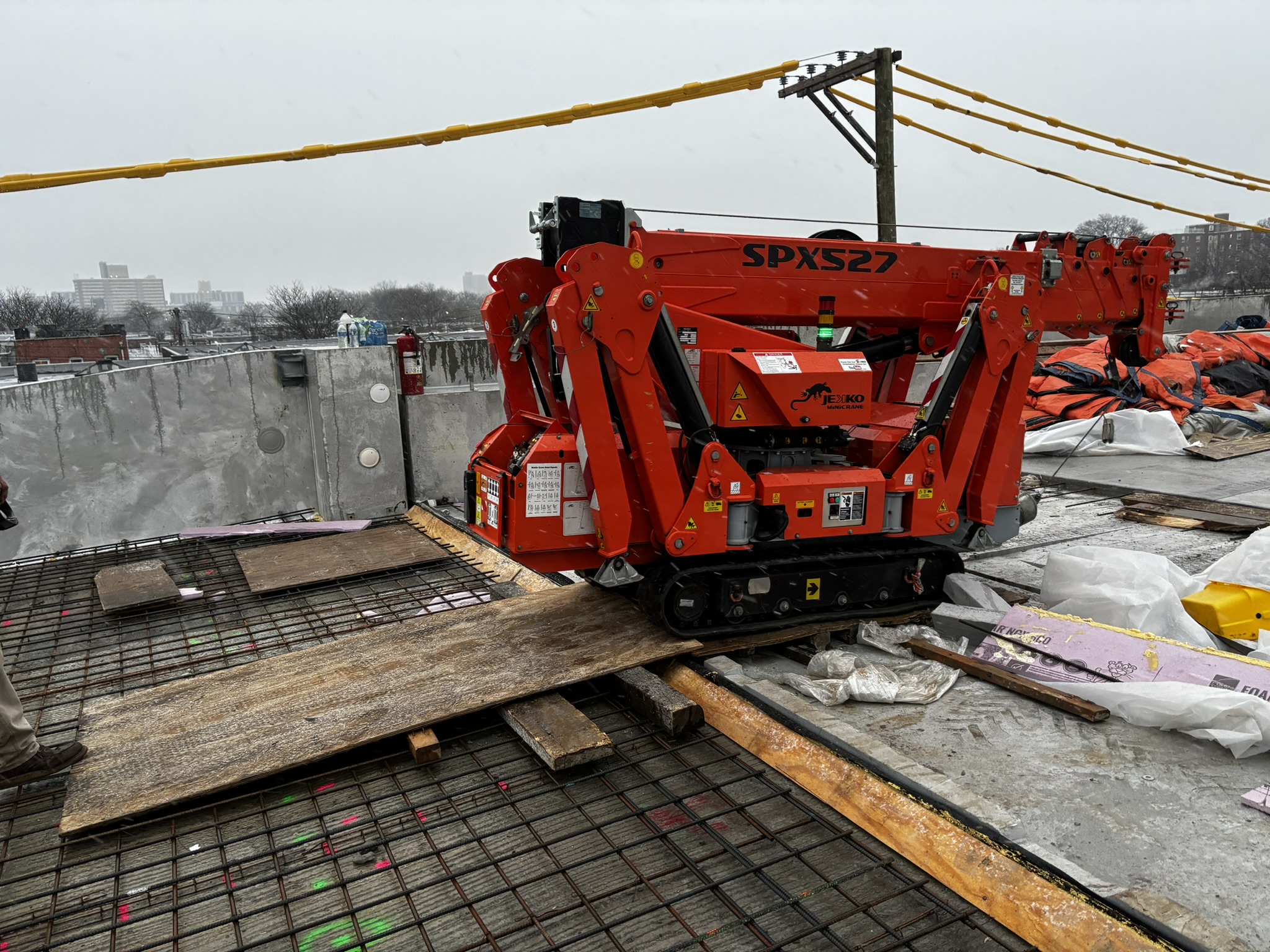 Jekko SPX527 spider crane tracking across plywood on a rooftop deck in tight urban access