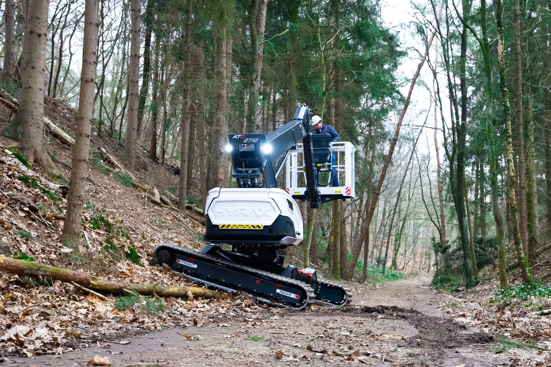 Hyrax tracked spider lift climbing a wooded slope with the platform raised